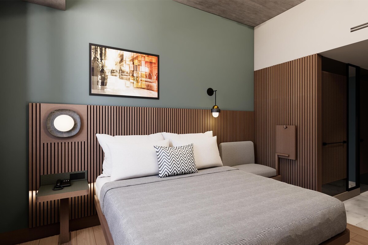 A modern bedroom with a bed, bedside table, lamp, and a framed picture on the wall.
