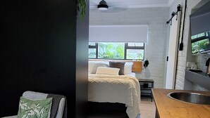 Una habitación moderna con una cama, una silla, una encimera de madera y un televisor.