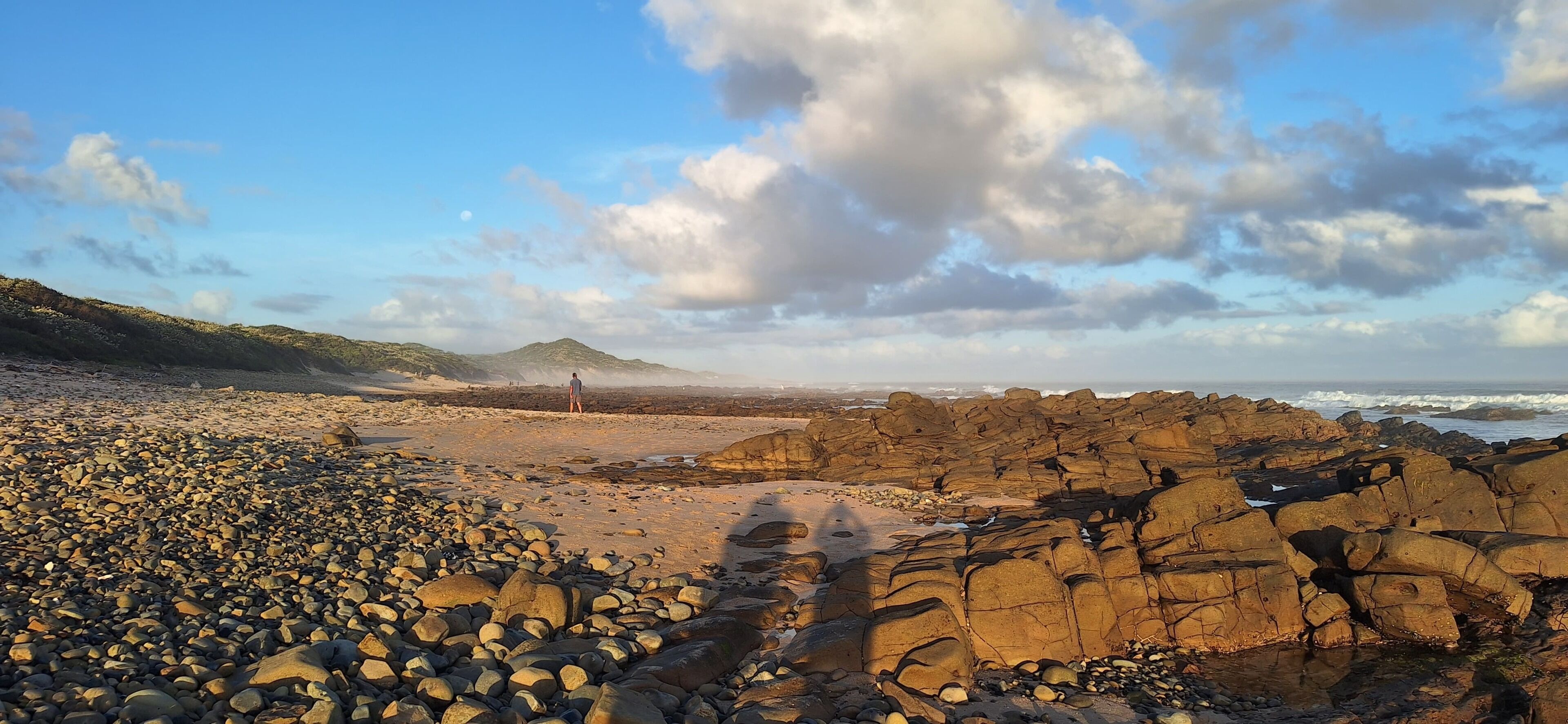 A rocky beach with a distant mountain and ocean view.