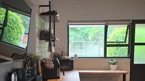 Una cocina moderna con una isla central, taburetes de madera, un ventanal grande y una lámpara en el techo.