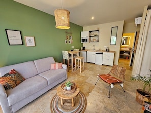 Un salon moderne comprenant un canapé, une table basse et un coin repas avec des chaises.
