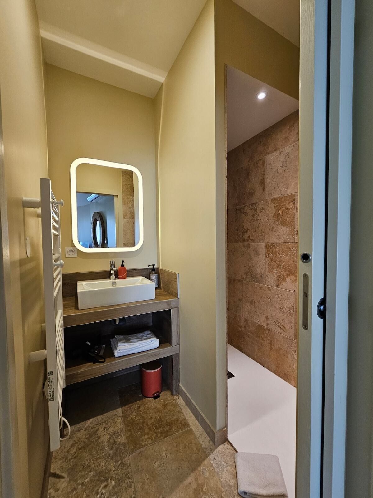 Un baño con lavamanos, espejo y zona de ducha.