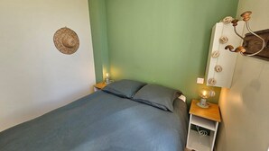 Un dormitorio con una cama, dos mesitas de noche, una lámpara de pared y un adorno colgante en la pared.