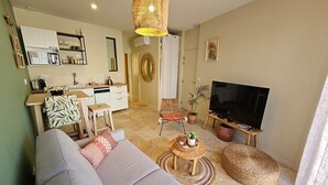 Una sala de estar con un sofá, un televisor, un comedor con mesa y sillas, y una cocina con fregadero y armarios.