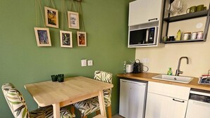 Eine kompakte Küche mit Essbereich, mit einem Holztisch und Stühlen, einer Mikrowelle, einem Spülbecken und einer kleinen Ablage mit Küchenutensilien.