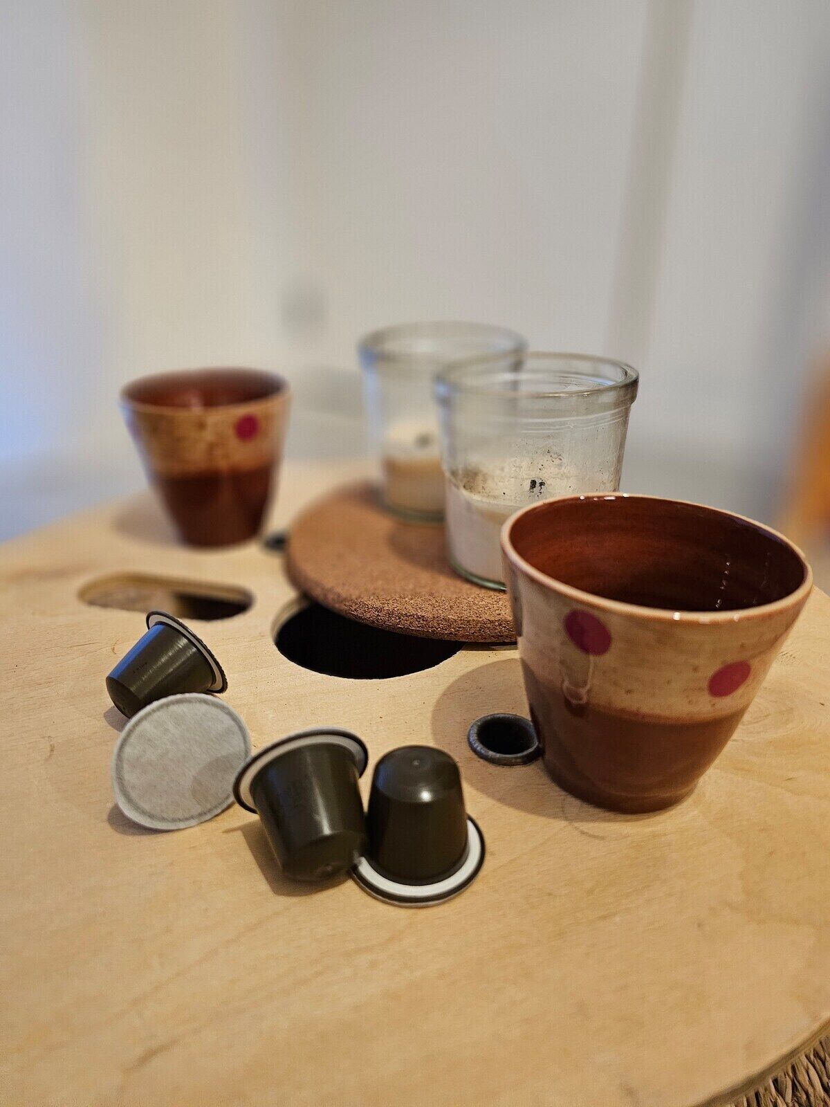 Una mesa de madera con varias tazas y recipientes, algunos con tapas y otros sin ellas.