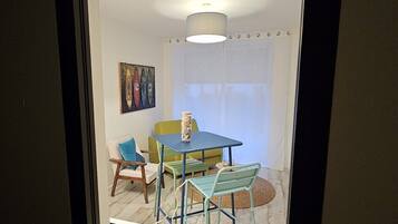 Una habitación con una mesa de comedor, sillas, un florero y un cuadro en la pared.