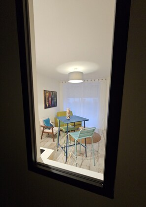 Una habitación con una mesa de comedor, sillas, un florero y un cuadro en la pared.