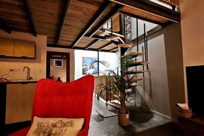 Un interior moderno con un sofá rojo, una escalera y una planta en maceta.