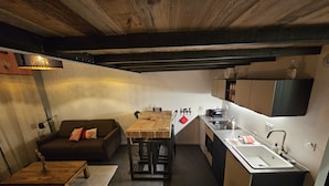 A compact kitchen with a dining table, a sofa, and a coffee table. - Le Chalet-Loft-Private Bathroom-Apartment-Garden view (Genas)