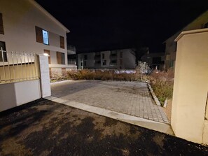 Un camino pavimentado que conduce a una entrada con puerta de rejas de un edificio con varias ventanas y balcones.
