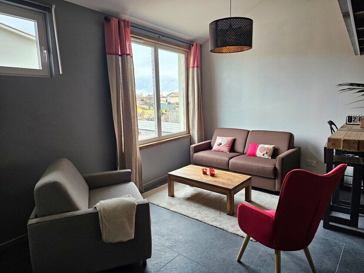 Een woonkamer met een bank, fauteuil, salontafel en een eettafel met stoelen.