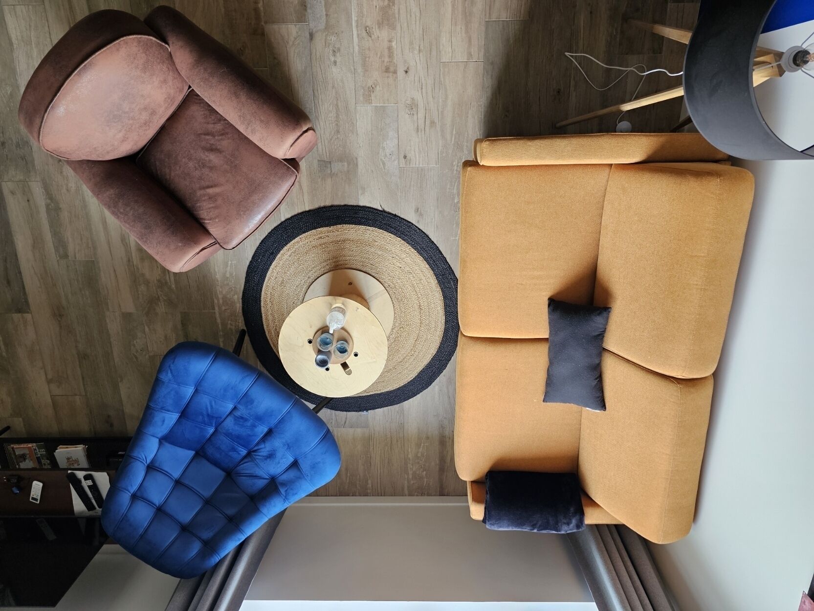 A modern living room with a brown sofa, a blue armchair, and a round coffee table with drinks.