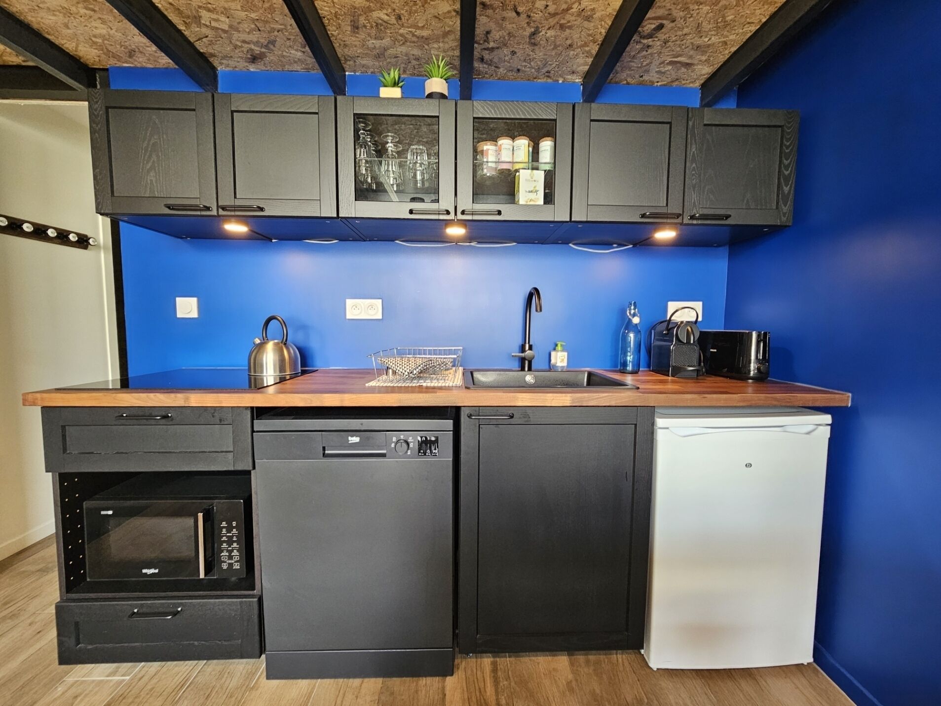 A compact kitchen with a dishwasher, oven, and sink.