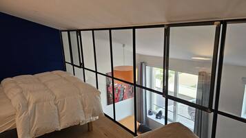 Un dormitorio con cama, ventana y vista al exterior.