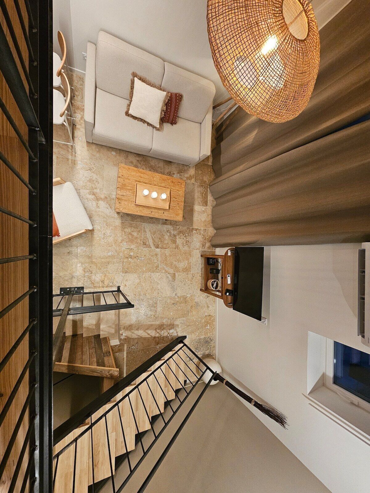 Ein modernes Interieur mit einer Treppe, einem Sofa, einem Holztisch und einer Pendelleuchte.