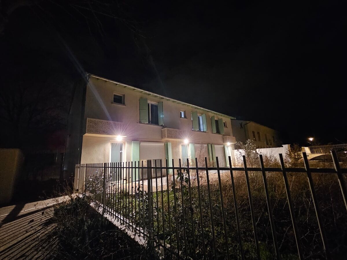 Ein zweistöckiges Gebäude mit geschlossenem Eingangsbereich und zahlreichen Fenstern, beleuchtet durch Außenbeleuchtung.