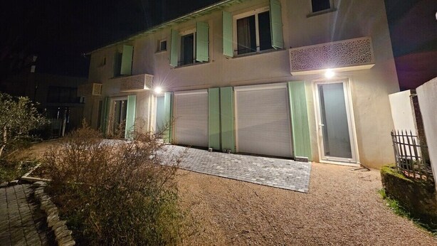 Un bâtiment à deux étages avec une allée en gravier et un petit jardin.