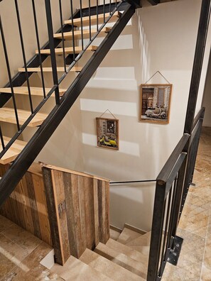 Eine Treppe mit Holzboden und schwarzen Geländern, die zu einer Zwischenebene mit zwei gerahmten Bildern führt.