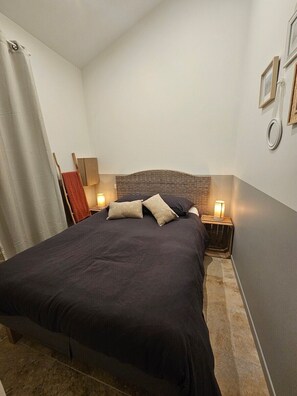 Ein Schlafzimmer mit einem großen Bett, zwei Nachttischlampen, einem Holz-Kopfteil und einem Vorhang.