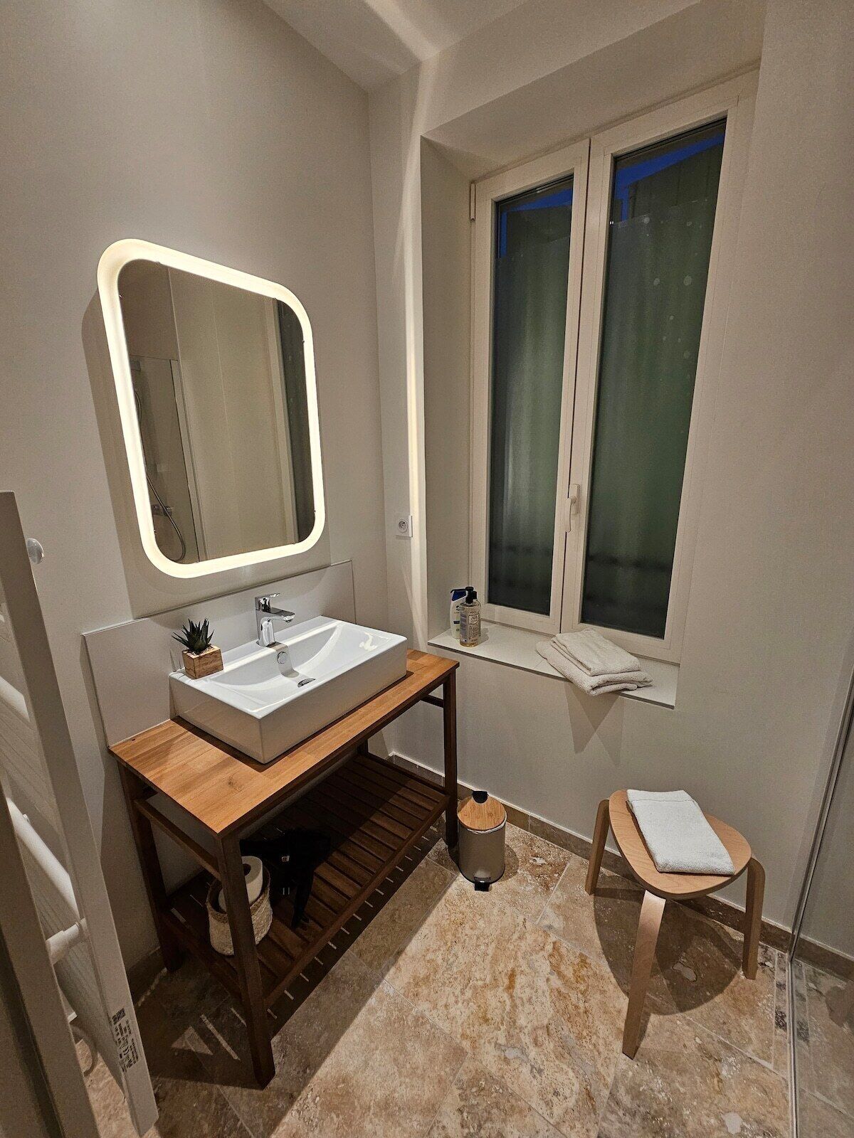 Une salle de bain moderne avec un grand miroir, un lavabo et une fenêtre.
