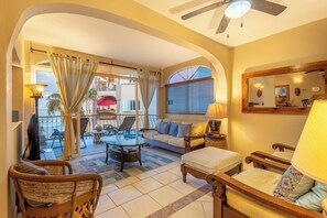 A spacious living area with a balcony, a sofa, a coffee table, and a TV. - Oceanfront 3BR Condo w/ Pool, Hot Tubs, Surf Breaks and Cortez Views (San José del Cabo)