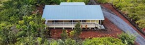 A two-story building with a flat roof, surrounded by dense vegetation. - Eco Ocean Oasis, Tropical 1-Acre Retreat with Pool, Hot Tub, AC, Lanai (Keaau)