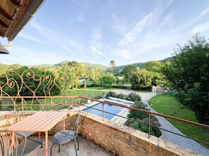 Eine Terrasse mit Pool, Sitzgelegenheiten im Freien und Blick auf eine üppige Landschaft.