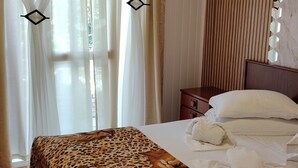 Un dormitorio con cama, cortinas, suelo de madera y cabecera.