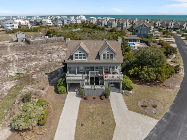 A two-story house with a front porch, a small deck, and a view of the ocean.