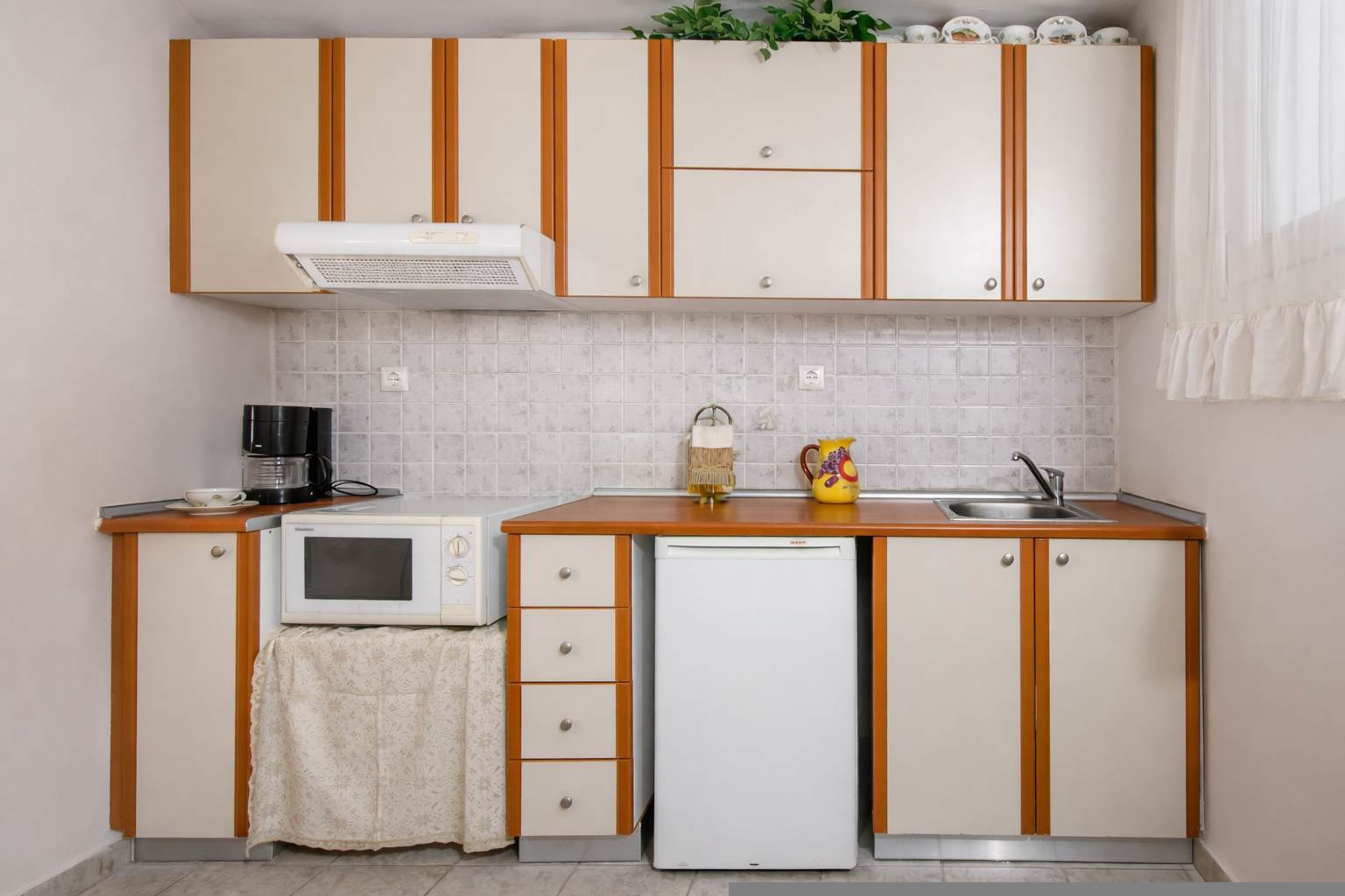 Uma cozinha compacta com micro-ondas, geladeira e pia.