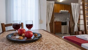 A room with a dining table set with apples, walnuts, and wine glasses. - Byzantine Vibe - Seaside Cozy Stay Near Volos (Volos)
