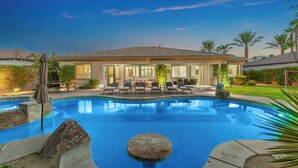 Una proprietà residenziale con piscina, area salotto esterna e giardino curato.
