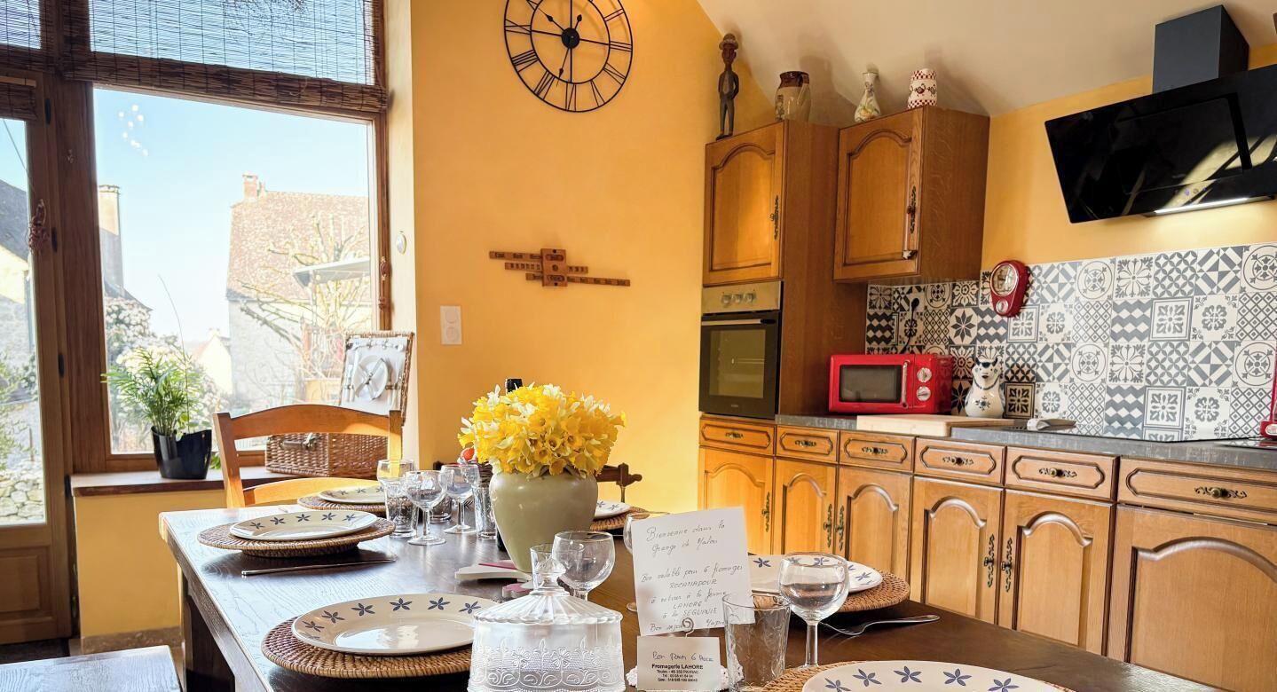 A kitchen with wooden cabinets, a clock, a microwave, and a tiled backsplash.