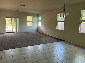 Una habitación amplia con piso alfombrado, paredes enlosetadas y una lámpara en el techo.