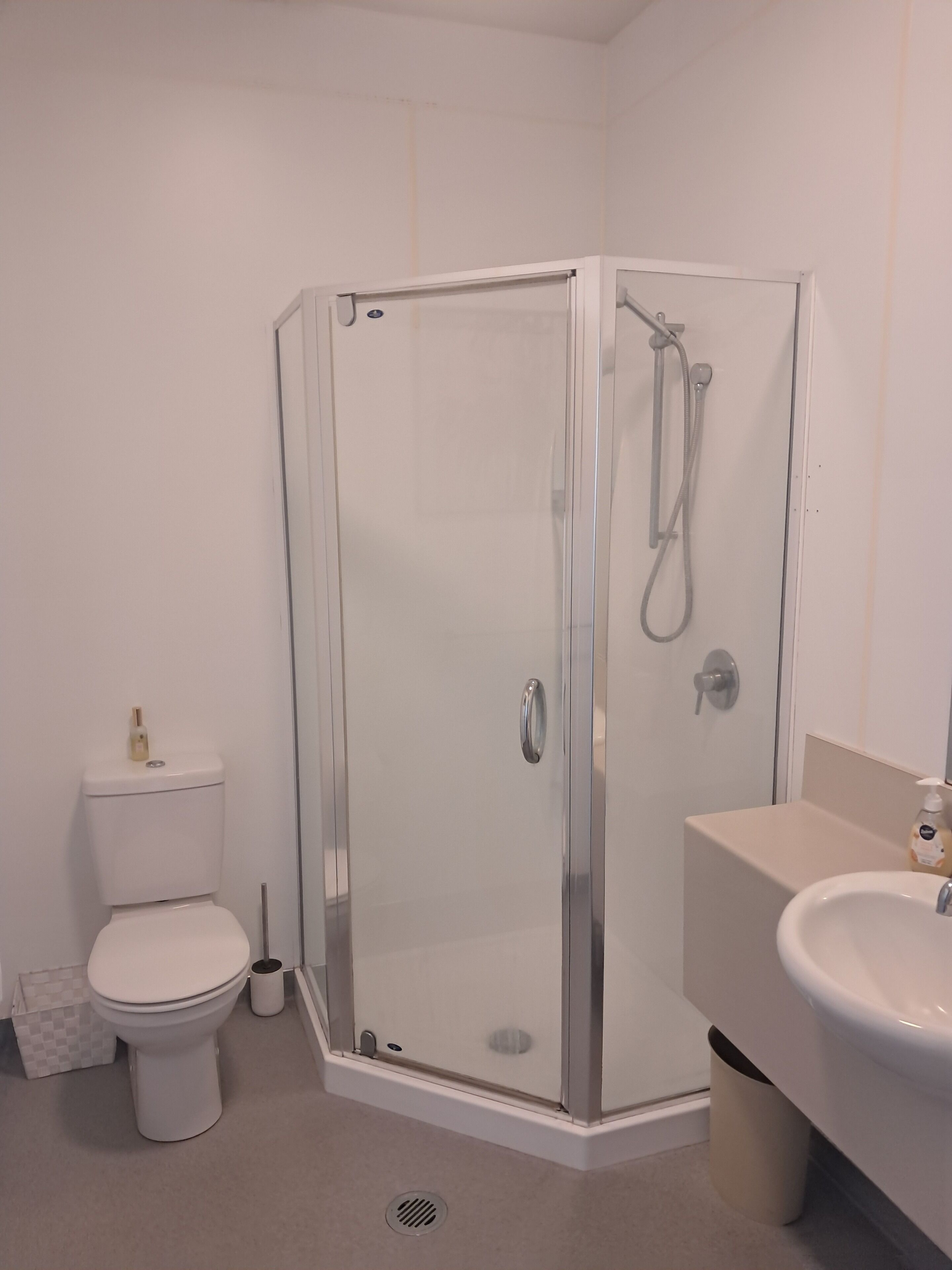 Et stilfuldt badeværelse med en glasafskærmet brusekabine, toilet og vask.
