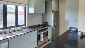 A modern kitchen with a built-in oven, a stainless steel refrigerator, and a window providing a view of the outside.