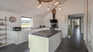 A modern kitchen with a central island, a clock on the wall, and a view to the outside. - Lovely home in Glesborg with WiFi (Glesborg)