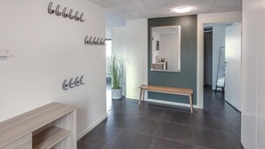A hallway with a bench, coat hooks, a potted plant, and a mirror on the wall. - Lovely home in Glesborg with WiFi (Glesborg)