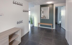 Ein Flur mit einer Bank, Kleiderhaken, einem Blumentopf und einem Spiegel an der Wand.