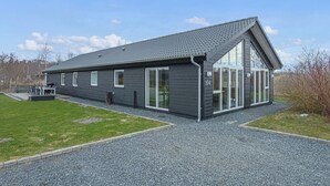 A modern building with a sloped roof, large windows, and a gravel driveway. - Lovely home in Glesborg with WiFi (Glesborg)