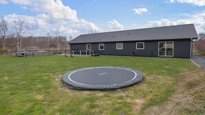A house with a trampoline in the yard, a covered outdoor seating area, and a large window. - Lovely home in Glesborg with WiFi (Glesborg)