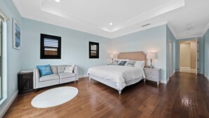 Een slaapkamer met een bed, nachtkastjes, een bank en een raam met jaloezieën.