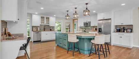 A spacious kitchen with a central island, white cabinetry, and a wooden floor.