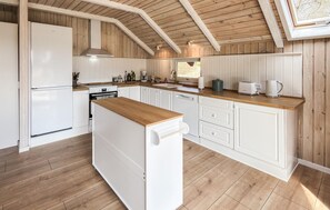 Una cocina con suelo de madera, armarios blancos, una isla central y un tragaluz.
