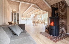 Una sala de estar acogedora con un sofá, una chimenea y una cocina al fondo.