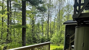 A wooden deck with a railing, a wicker chair, and a small shed.