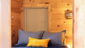 A wooden cabin bedroom with a bed, pillows, and a nightstand.