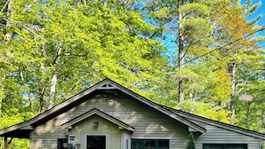 A small, single-story cabin with a front door, a small porch, and a window.