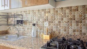 A kitchen with a patterned backsplash, a stainless steel sink, a water dispenser, and a gas stove. - Peaceful place near stadium and airport (Tanger)